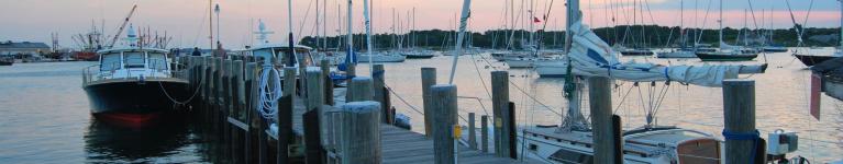 Photo of sailboats at dock with sunset sky in background